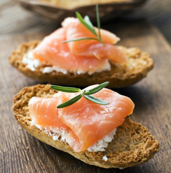 Healthy Norwegian salmon snack with goats cheese and rosemary on wholemeal