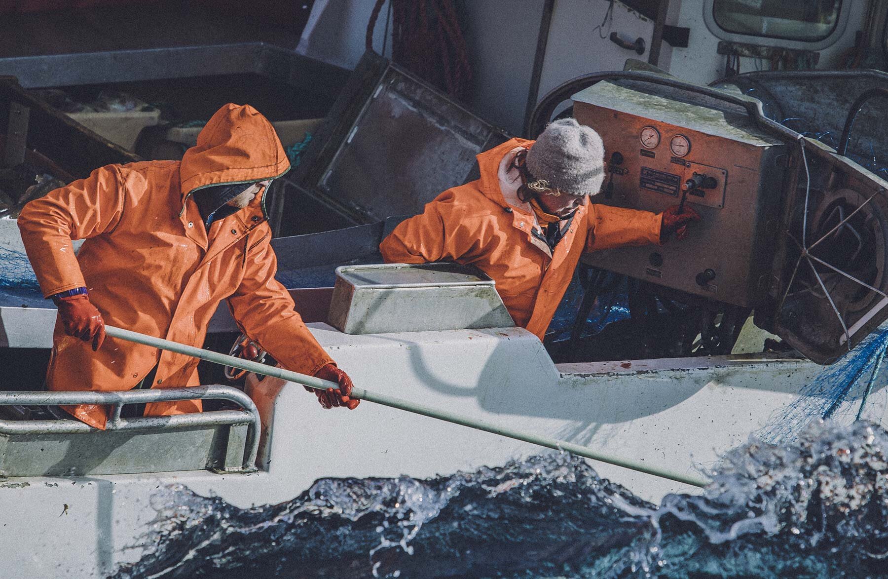 Fishermen on the side of a boat in rough seas